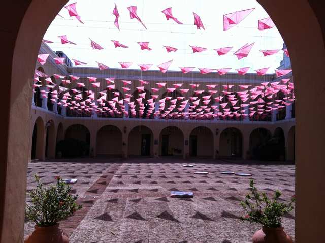 An arched courtyard with hundreds of small pink flags stretched overhead.