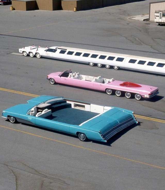 Three unusually elongated custom cars are parked on an open paved lot.