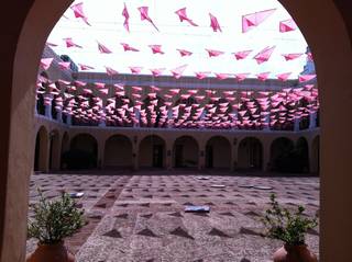 An arched courtyard with hundreds of small pink flags stretched overhead.