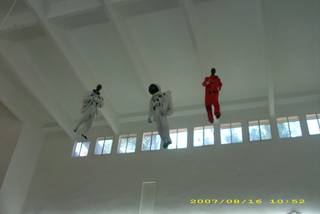 Three astronaut-suited figures suspended near the ceiling of a white interior.