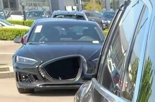 A dark car with a large empty black opening in its front grille.