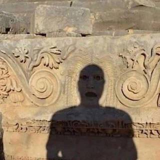 An anonymous head-and-shoulders shadow on carved stone, with apparent eyes and an open mouth.