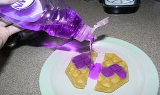 Bright purple liquid is poured onto waffles.