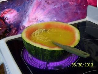 Watermelon bowl filled with yellow soup.