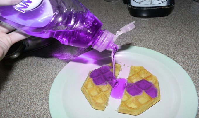 Bright purple liquid is poured onto waffles.