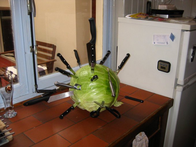 Green object pierced with kitchen knives.