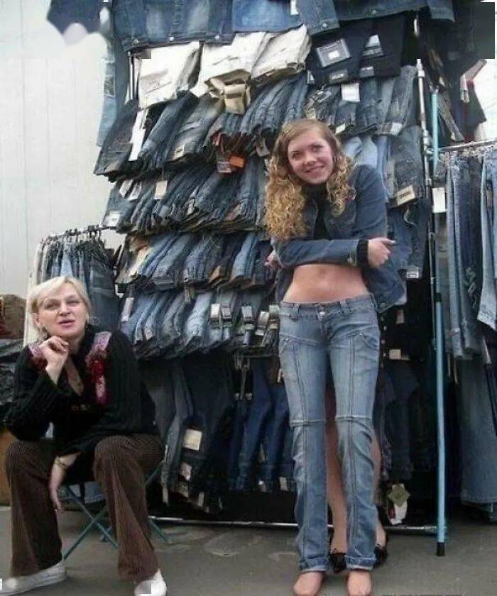 Two people standing in front of a tall wall of shoes.