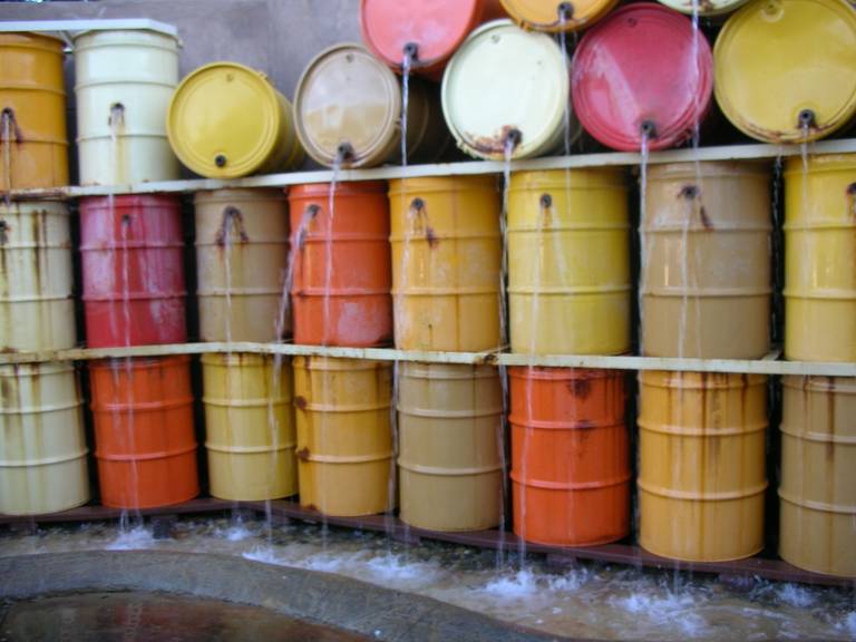 Rows of yellow, orange, pink, and white barrels stacked against a wall.
