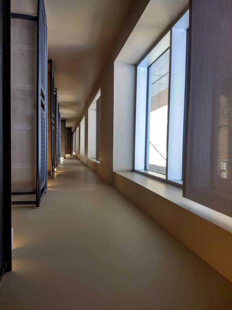 An empty stairwell viewed downward, with windows, railings and steps aligning like a hallway.