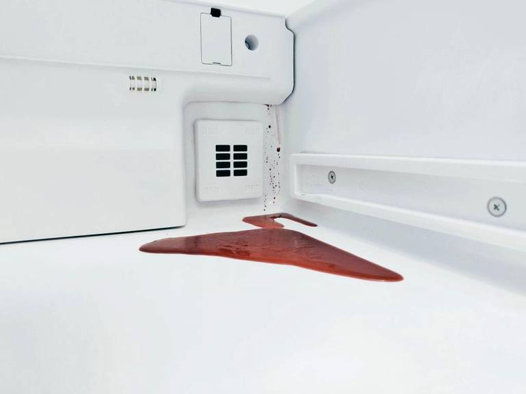 A red beetroot spill pools inside a white refrigerator.