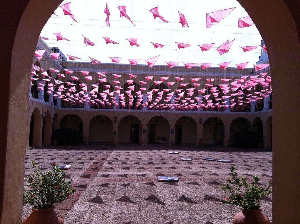 An arched courtyard with hundreds of small pink flags stretched overhead.