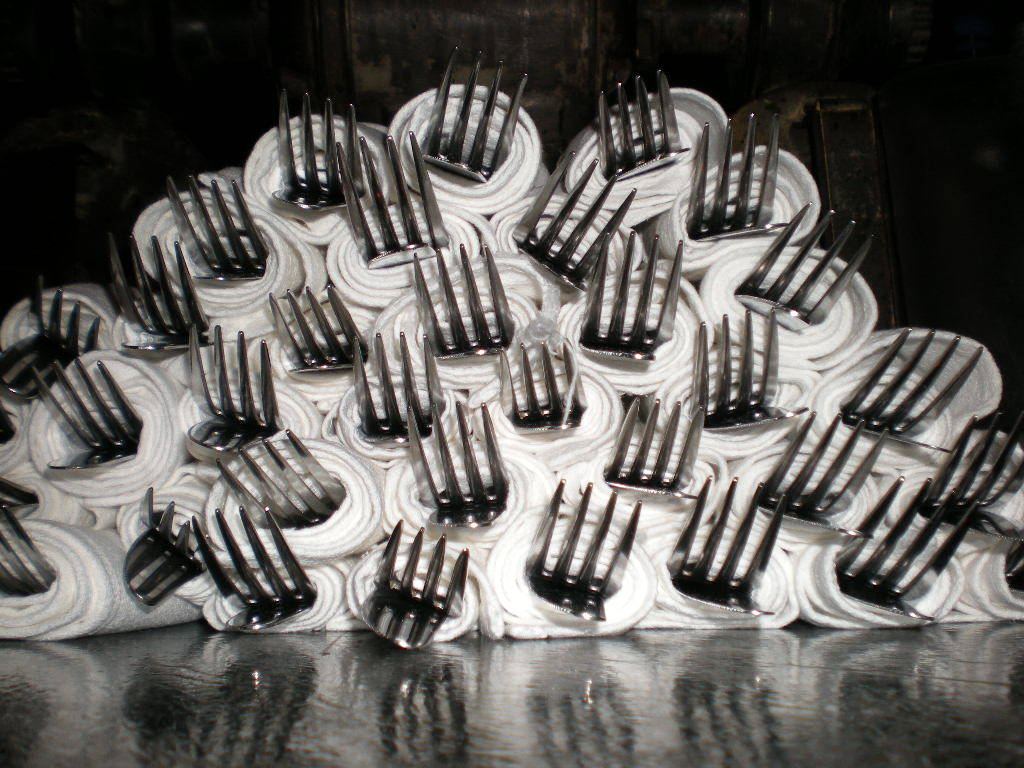 A white frosted cake covered in many upright metal forks.