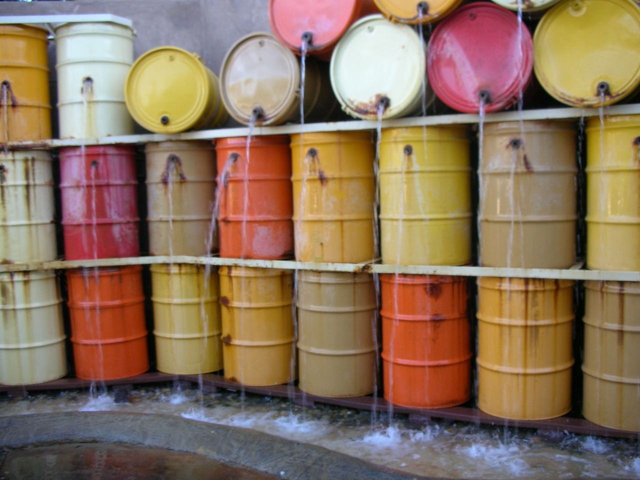 Rows of yellow, orange, pink, and white barrels stacked against a wall.