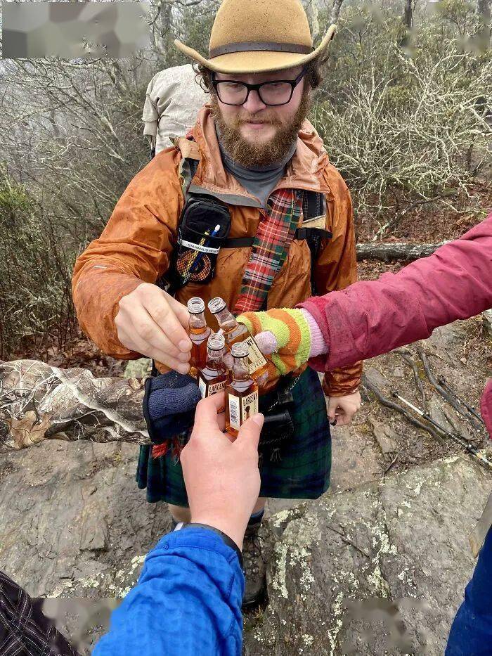 A person in a white shirt carrying a child facing backward near water.