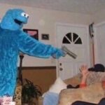 Cookie Monster costume character with a gun in a bizarre scene.