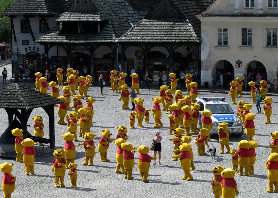 Hundreds of Winnie the Pooh mascots in a town square surrounding a police car.