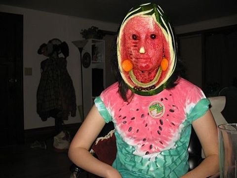 Cursed image of a human with a watermelon mask in a dimly lit room.