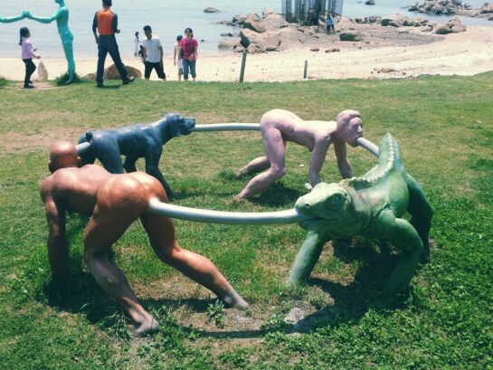 A park sculpture of humans and an iguana connected in a circular loop.