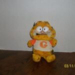 A damaged Garfield plushie with uneven eyes sitting on a table.