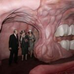 Visitors inside a giant human mouth-themed exhibit, exploring its interior.