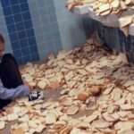 Man Sitting Among Slices of Bread in a Bathroom