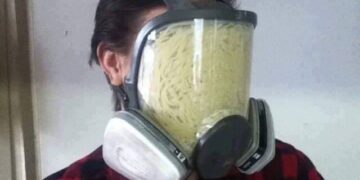 Pasta stuffed inside a gas mask in a strange and cursed setup.