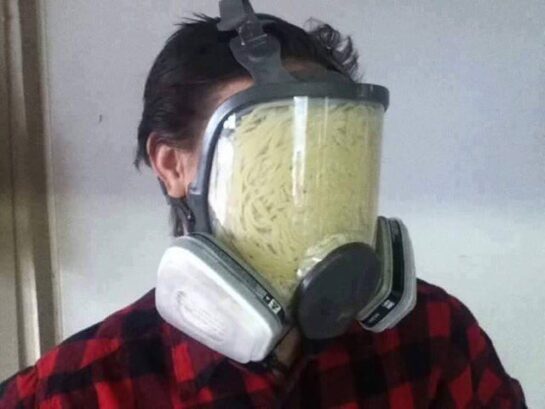 Pasta stuffed inside a gas mask in a strange and cursed setup.