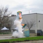 Cursed image of a fiery porta-potty explosion near a white building.