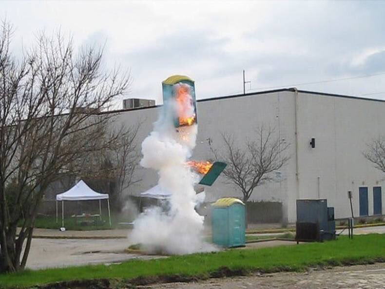 Porta-Potty Launches Into the Air: A Cursed Image 4 Cursed image of a fiery porta-potty explosion near a white building.