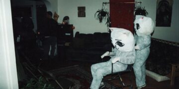 Two people dressed as cats, one pushing the other in a wheelchair.